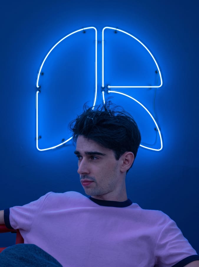 Philippe de Roquefeuil devant le monogramme R en néon bleu